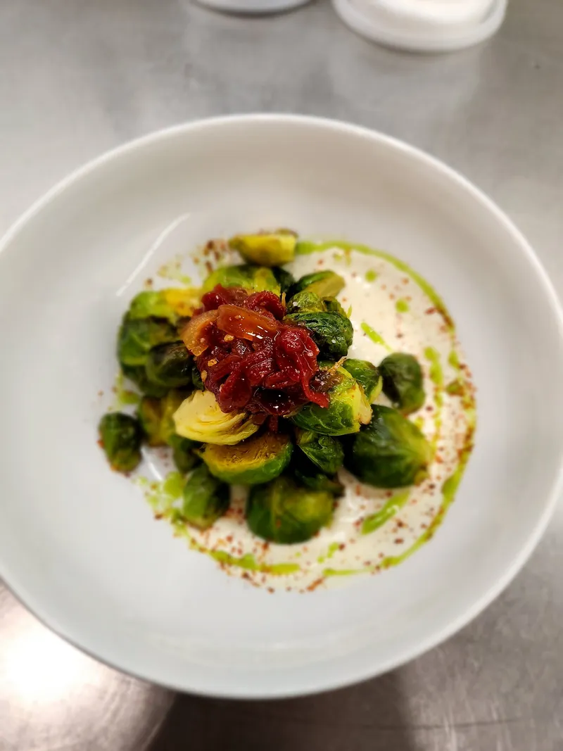 Charred brussels sprouts plated over a creamy base